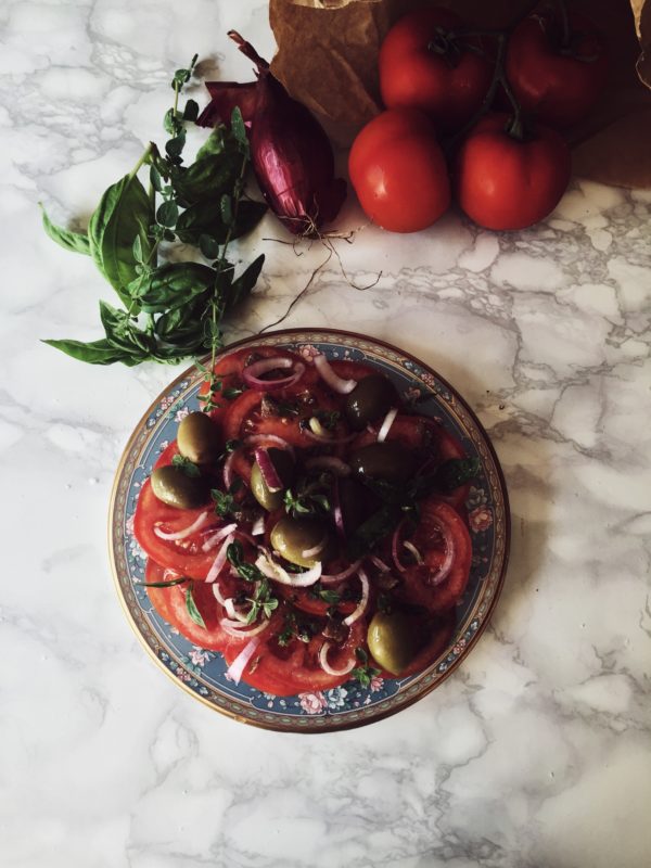 una saporita insalata di pomodori, con olive, capperi, acciughe, e basilico e origano freschi