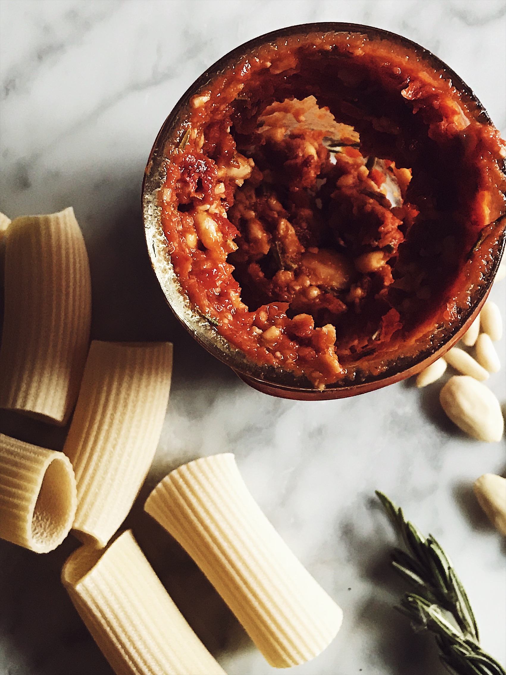 sun dried tomatoes pesto in the blender bowl, raw pasta, and pine nuts