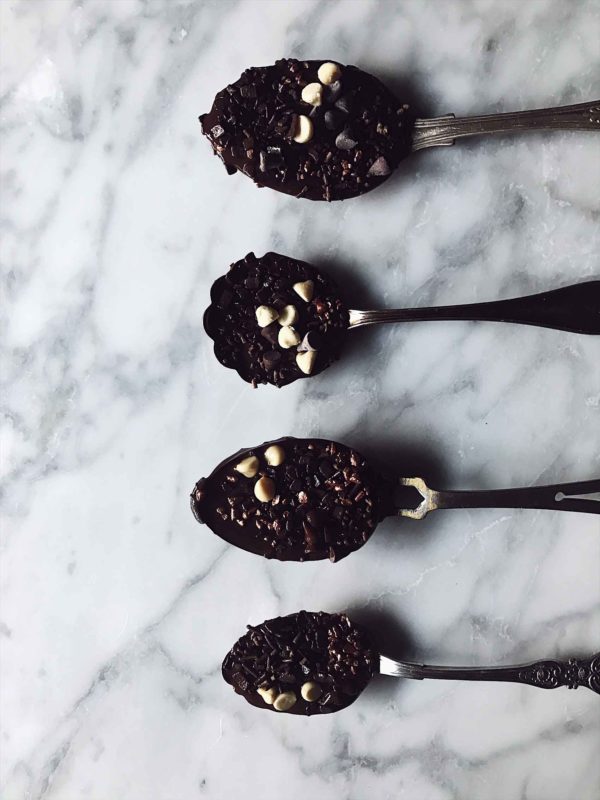 Chocolate covered spoons on a marble surface