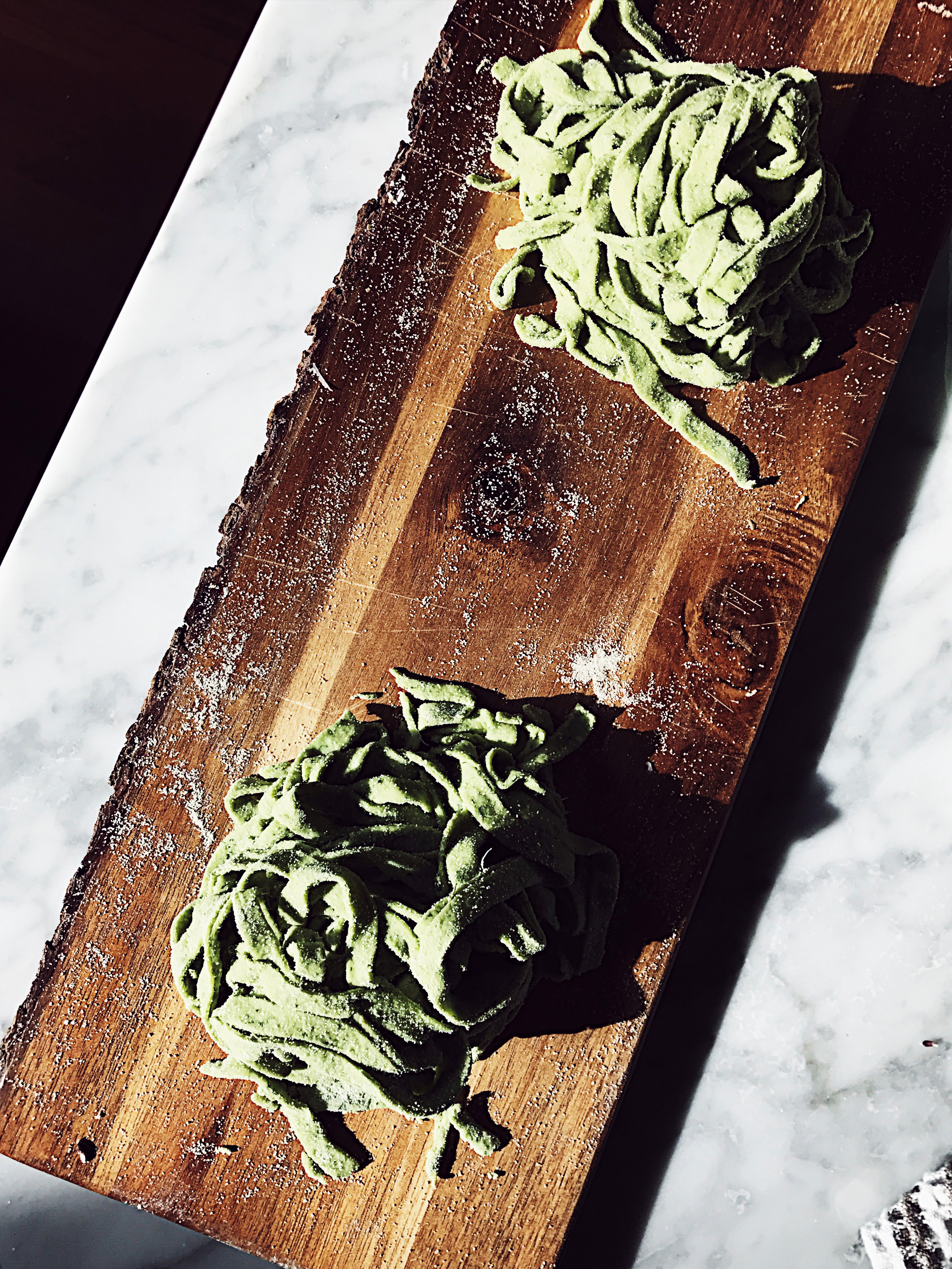 homemade green pasta nests on a wooden cutter