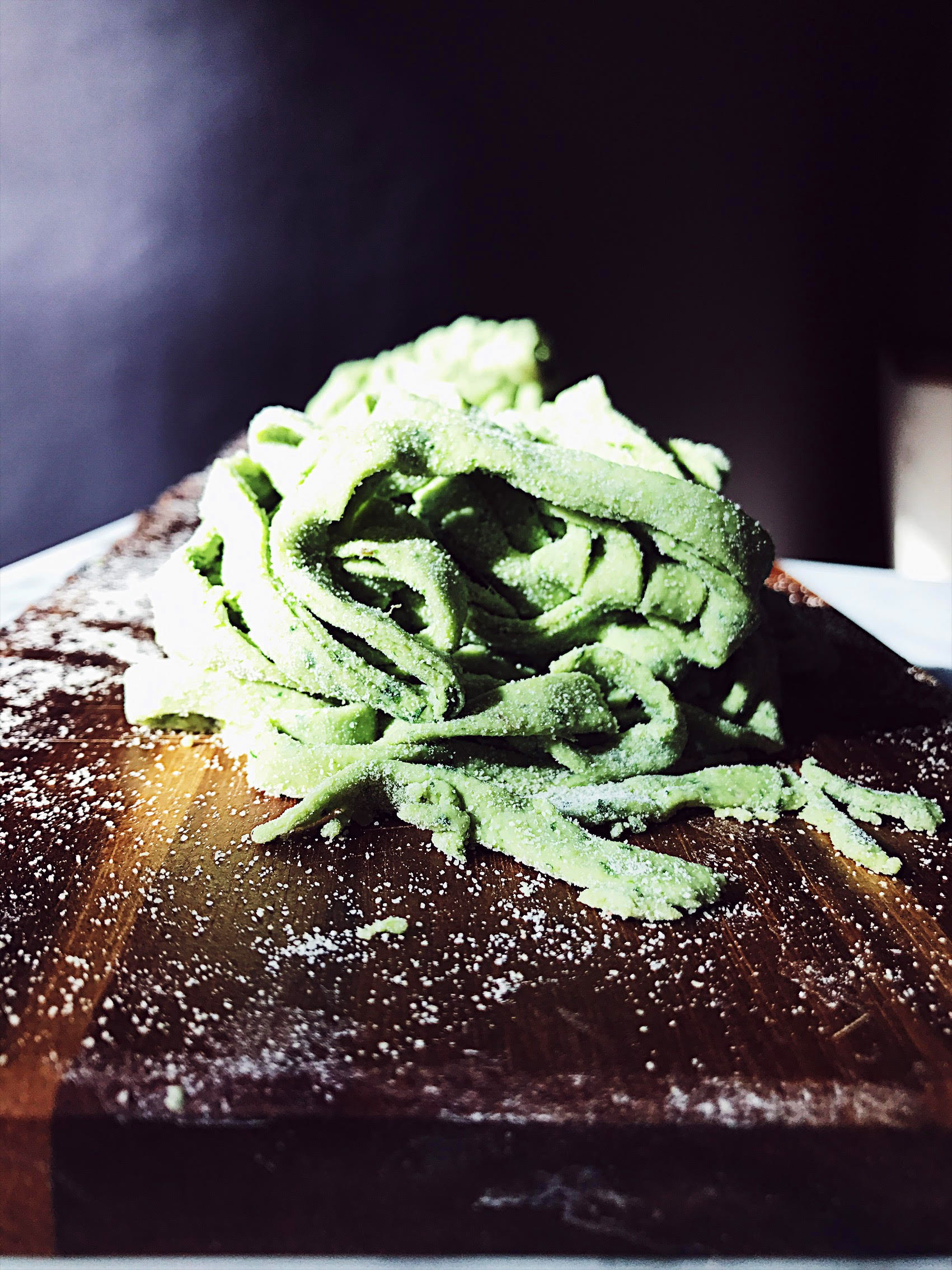 green homemade pasta on a wood cutter