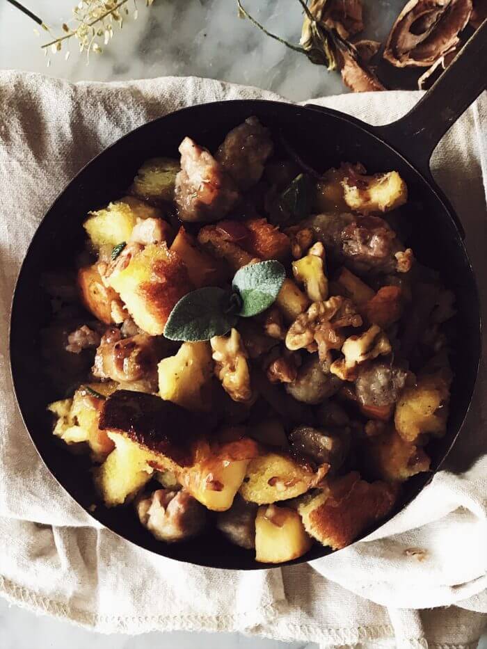 Italian Thanksgiving sausage stuffing in a pan on a table with apples and dried flowers