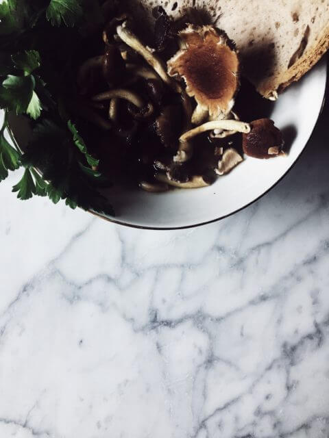 Mushroom soup with a slice of bread and fresh parsley in a white bowl