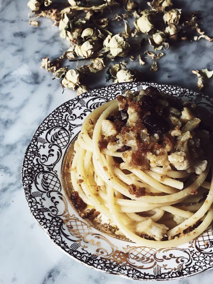 Sicilian pasta with cauliflower, raisins, anchovies, breadcrumbs, saffron, and pine nuts on a golden vintage plate