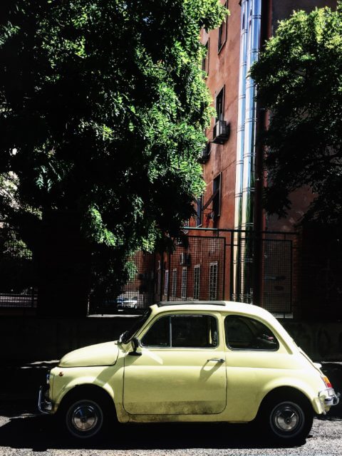 Ferragosto in Rome: a lonely yellow cinquecento car in a desert street