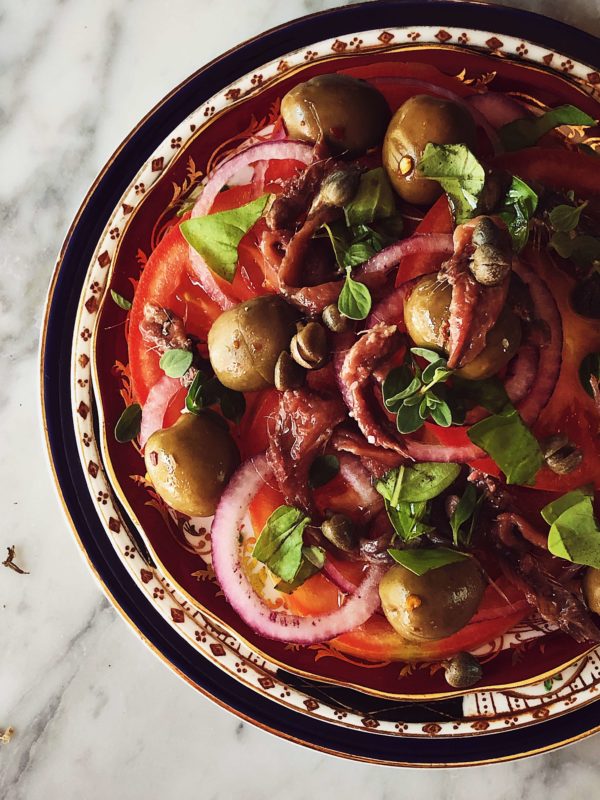 tomato and red onion salad on a red fine china plate