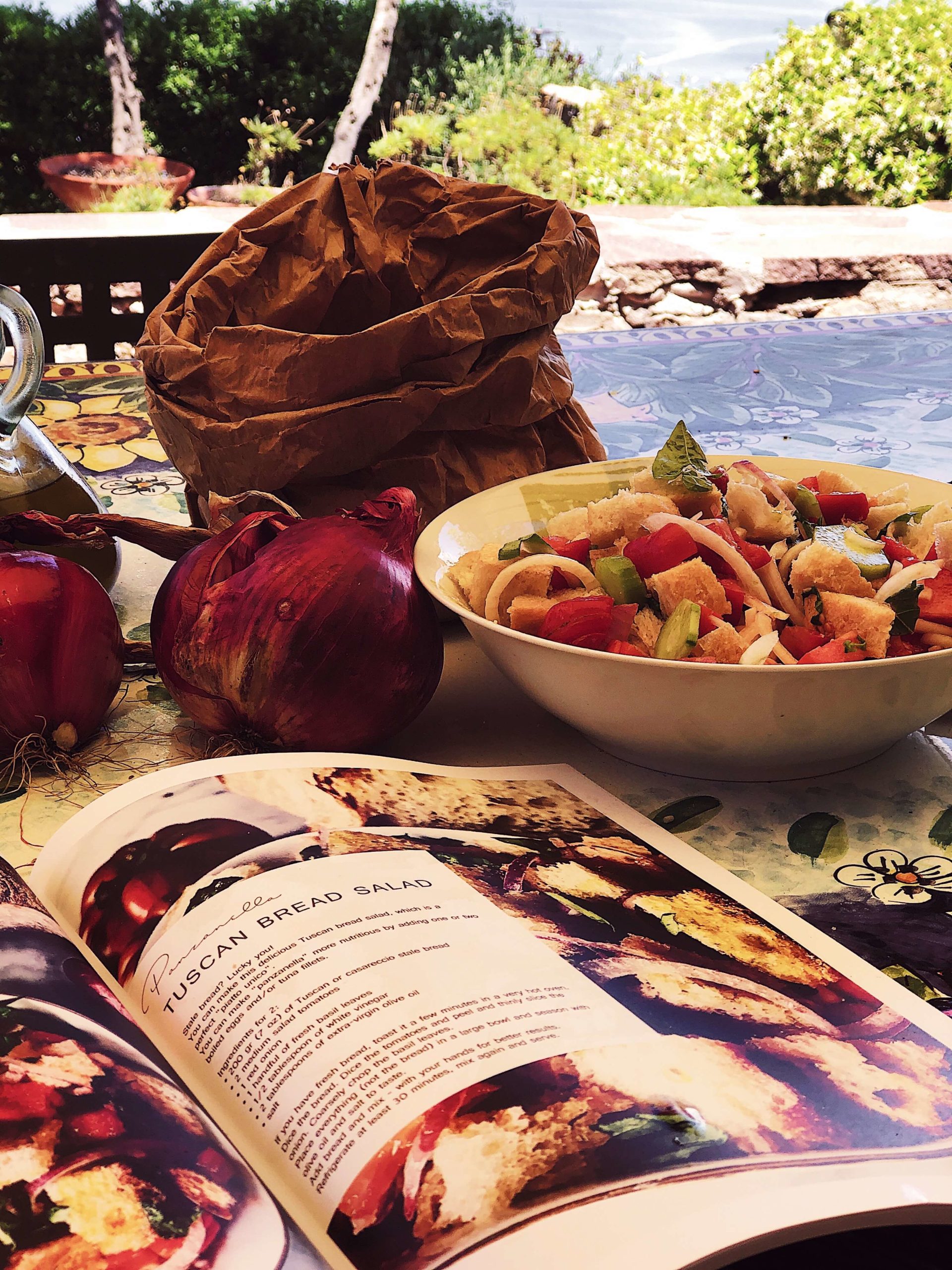 panzanella salad in a white bowl next to the Simposio Italian cooking magazine
