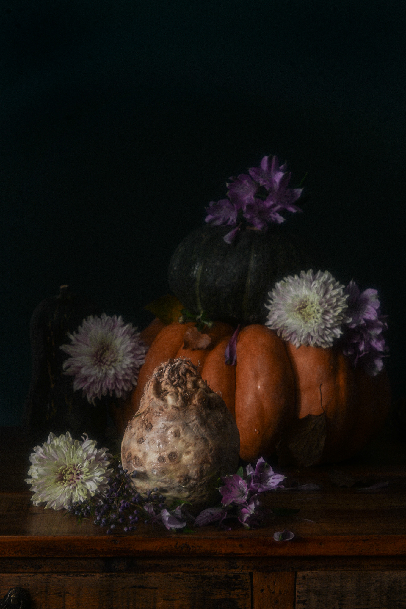 dead-pumpkin-blues-italian-autumn-still-life Dark autumn still life with orange and green pumpkins, a knobbly celeriac and purple and pale flowers arranged on an antique wooden surface.
